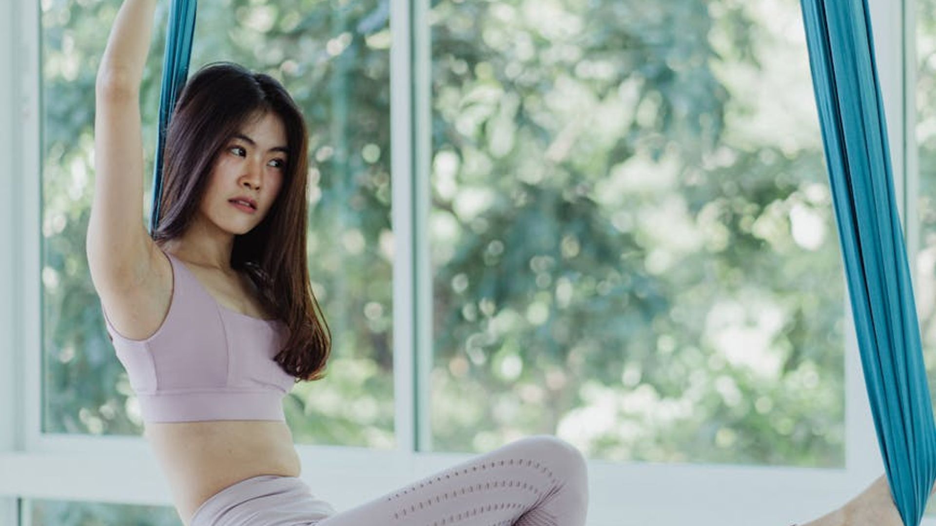 Serene woman practicing yoga in a bright olive studio.